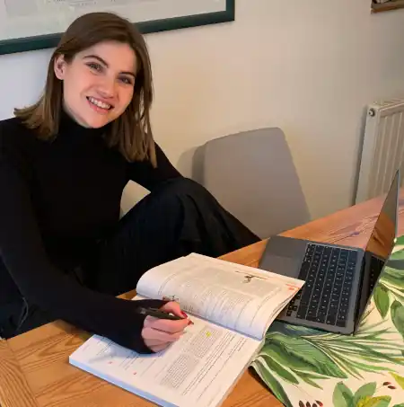 Studentin lernt online mit Kursbuch und Computer